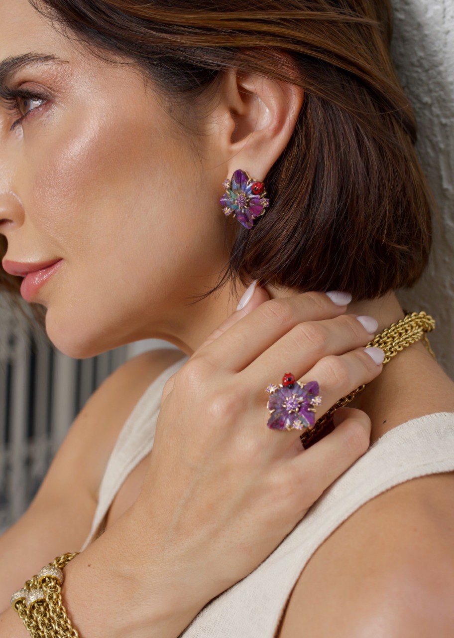 Modelo com brincos e anel de flor em tons de roxo