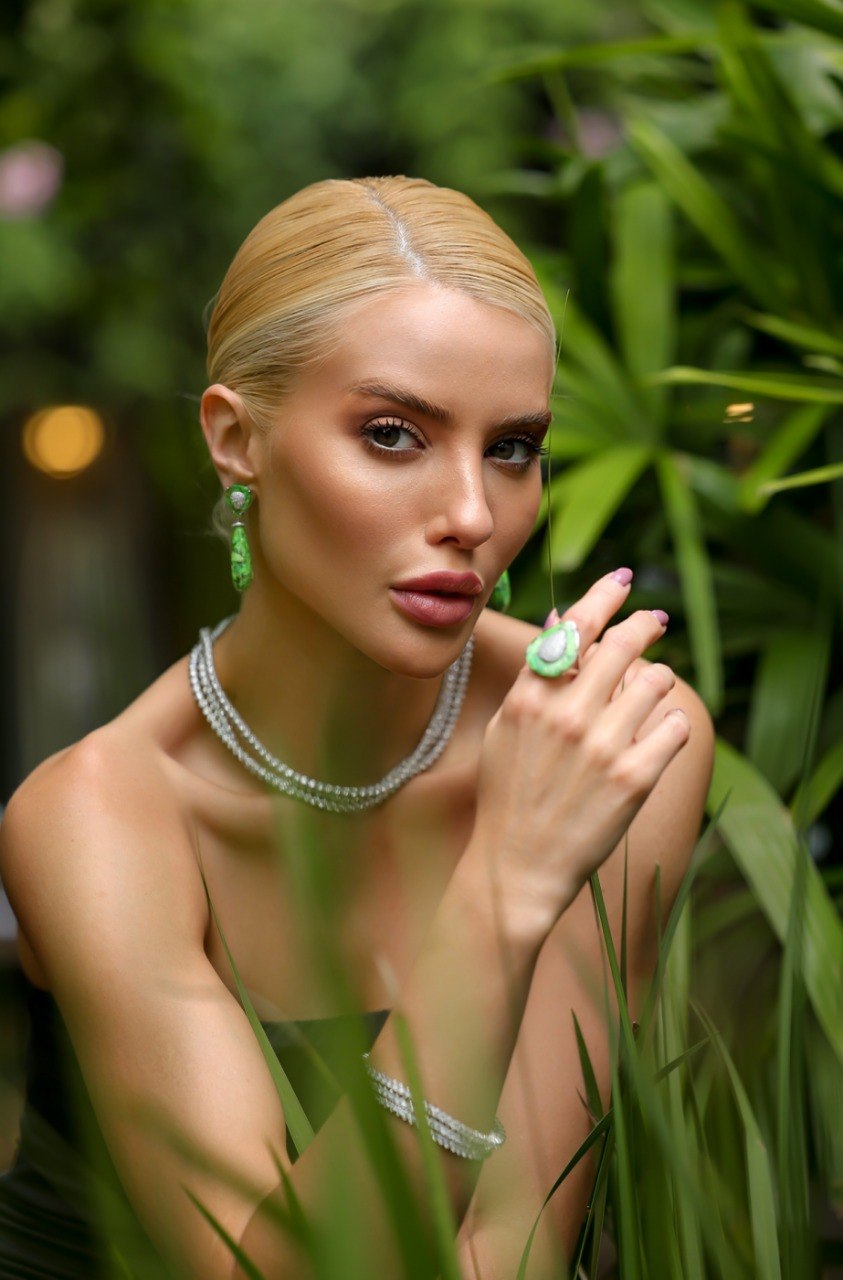 Modelo com anel e brincos verdes em jardim